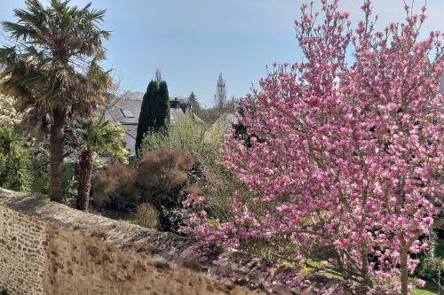 a garden with pink flowers and palm trees at Hôtel Ginkgo - SPA Biloba in Quimper