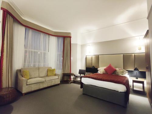 a hotel room with a bed and a couch at Blue Bells Hotel in London