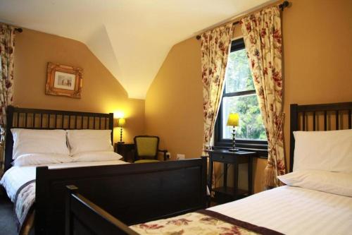 1 dormitorio con 2 camas y ventana en Knockninny Country House, en Derrylin
