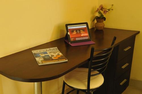 a table with a laptop and a book on it at Regent Suvarnabhumi Hotel in Lat Krabang