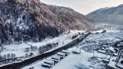 a village covered in snow next to a mountain at Complex Lunlo Village in Brezoi