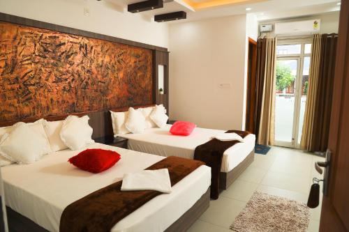 twee bedden in een hotelkamer met een schilderij aan de muur bij Green Valley Residency in Kattappana