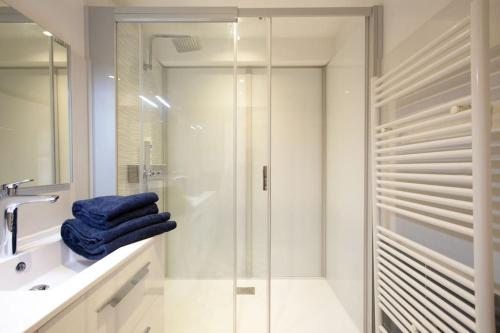 La salle de bains est pourvue d'une douche vitrée et de serviettes bleues. dans l'établissement Appartement Gambetta, à Saint-Jean-de-Luz