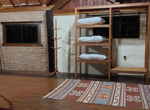 a room with a shelf with pillows on a rug at Chalé da Serra in Bragança Paulista