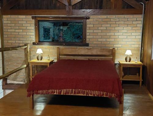 a bedroom with a bed and two tables with lamps at Chalé da Serra in Bragança Paulista