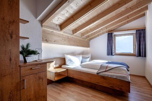 a bedroom with a wooden bed and a window at Bergchalet Haflingerherz in Wenns