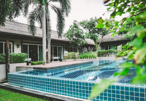 a swimming pool in front of a house at Nirundorn Resort Chaam in Cha Am