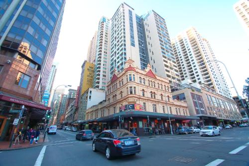 a car driving down a city street with tall buildings at Sydney Central Inn in Sydney