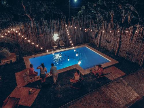 een groep mensen die 's nachts rond een zwembad zitten bij Hotel Xa´an Bacalar in Bacalar