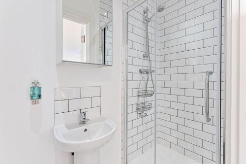 a white bathroom with a sink and a shower at The Nest - with Parking! in Swansea