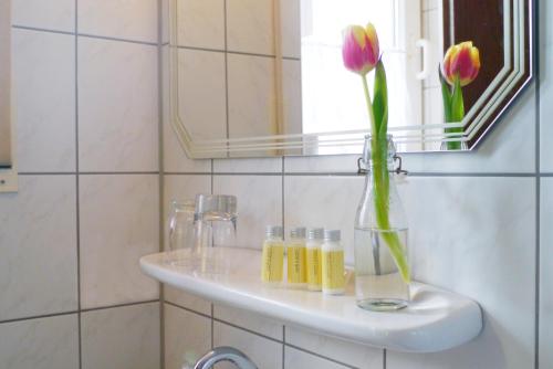 a bathroom sink with a vase with flowers in it at Landgasthof Zum Hirschen in Kemnath