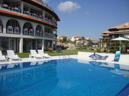a swimming pool in front of a building with chairs at Apolonia Apartments in Sozopol