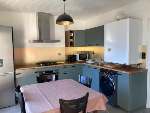 uma cozinha com armários azuis e uma mesa com cadeiras em Gîte partagé em Tresserves