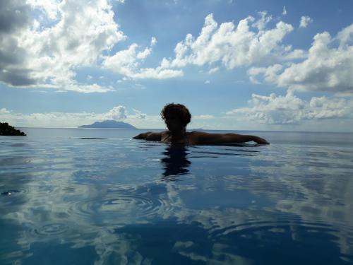 a man in the water in the ocean at Treasure Cove Hotel & Restaurant in Bel Ombre