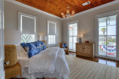 una camera da letto con letto, finestre e lampadario a braccio di The White House Galveston a Galveston
