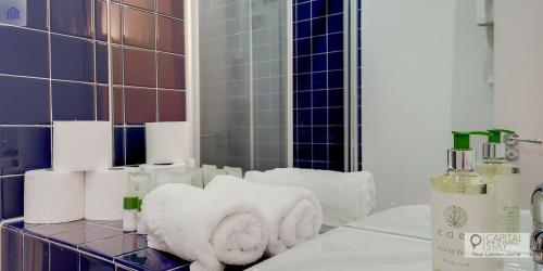 a pile of towels on a bathroom counter in front of a mirror at Capital Stay Aldgate - Two bed Apartment in London