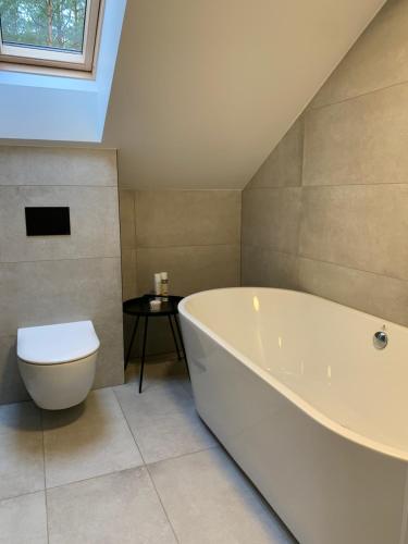 a bathroom with a white tub and a toilet at Sangrita Nida ADULTS ONLY in Nida