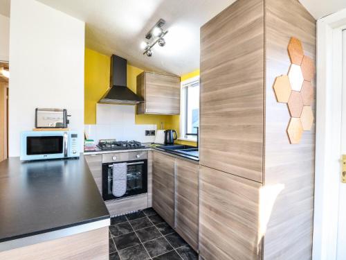 a kitchen with wooden cabinets and a black counter top at Kelpie in Lochgilphead