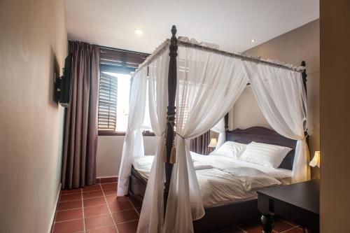 1 dormitorio con cama con dosel y cortinas blancas en Armenian Suite, en George Town