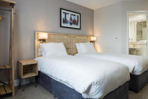 a hotel room with two beds and a mirror at The Raven’s Cliff Lodge by Marston's Inns in Motherwell