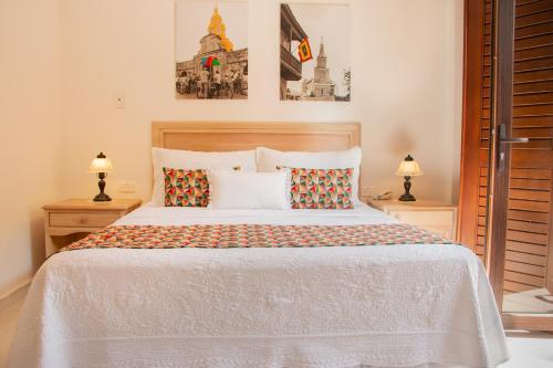 a bedroom with a large white bed with two lamps at Hotel Casa La Fe in Cartagena de Indias