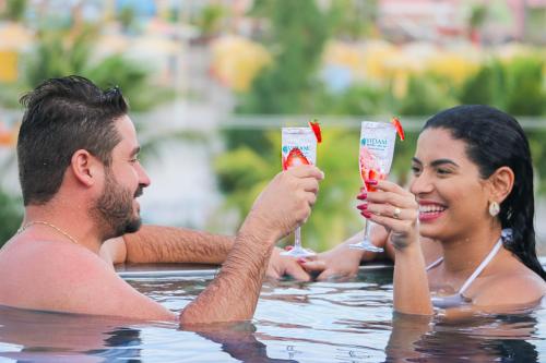 a man and woman drinking cocktails in a swimming pool at VIDAM Hotel Aracaju in Aracaju