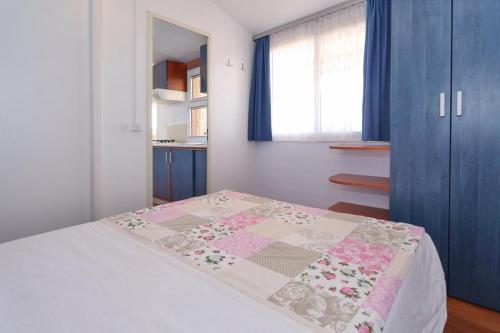 um quarto com uma cama com uma colcha em Poolside Mobile Home em Turanj