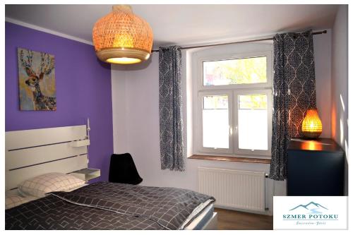 een slaapkamer met paarse muren, een bed en een raam bij Szmer Potoku in Świeradów-Zdrój
