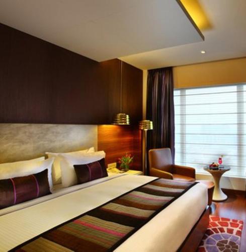 a hotel room with a large bed and a chair at Park Plaza Shahdara in New Delhi