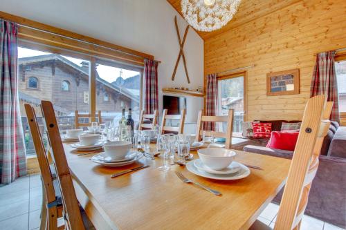 une salle à manger avec une table en bois, des verres et des chaises dans l'établissement Les Aiguilles - Snow and Trek, à Morzine