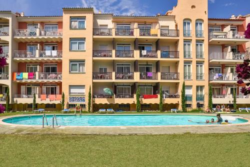 a hotel with a swimming pool in front of a building at Aptos. Comte D´Empuries in Empuriabrava