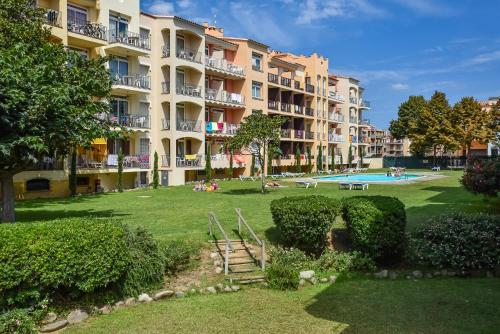 a large apartment building with a lawn and a swimming pool at Aptos. Comte D´Empuries in Empuriabrava