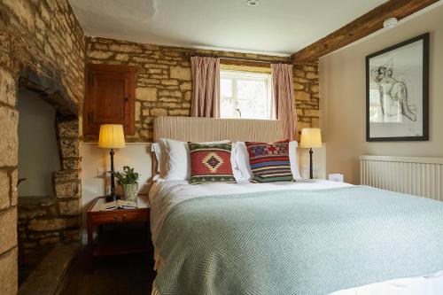 a bedroom with a large bed with pillows at The Lamb Inn in Shipton under Wychwood
