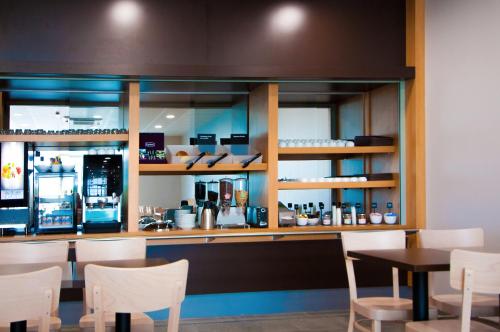 a restaurant with a counter with chairs and a table at B&B HOTEL La Rochelle Beaulieu Puilboreau in Puilboreau