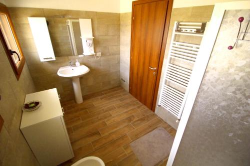 un bagno con lavandino, water e specchio di B&B Ca' Bianca ad Adria