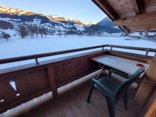 a table and a chair on a balcony with snow at Ferienhotel Alpenhof in Aurach bei Kitzbuhel