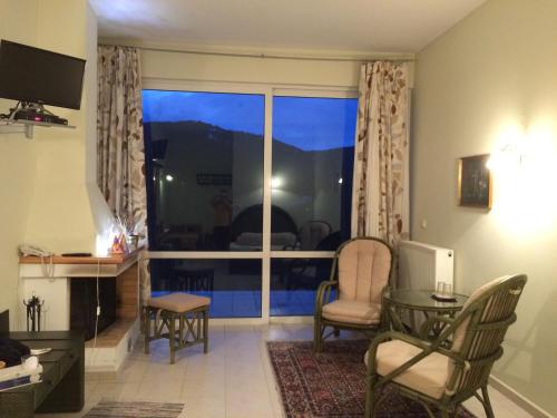 ein Wohnzimmer mit einem Fenster, einem Tisch und Stühlen in der Unterkunft Anarada Guesthouse in Synikia Mesi Trikalon