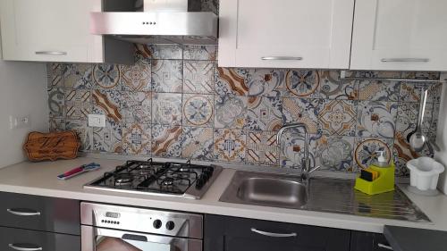 a kitchen with a stove and a tile wall at Villa Laura Salento in Marina di Pescoluse