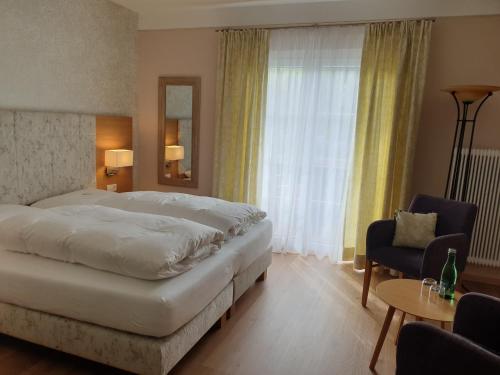 a bedroom with a bed and a chair and a window at Pension Alpenhof in Bad Aussee