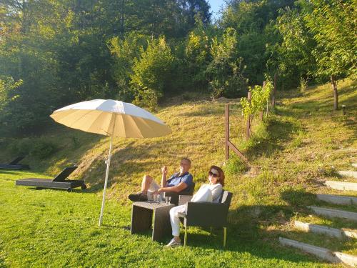 a man and woman sitting in chairs under an umbrella at Pension Alpenhof in Bad Aussee