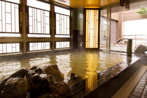 a pool of water with rocks in a room with windows at Dormy Inn Premium Shimonoseki in Shimonoseki