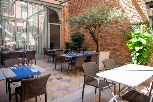 un patio avec des tables et des chaises et un mur en briques dans l'établissement Grand Hôtel d'Orléans, à Toulouse
