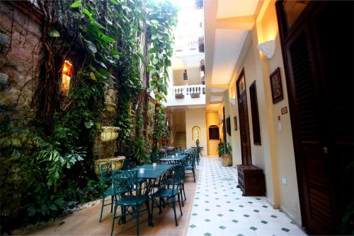 a row of tables and chairs in a building with plants at Hotel Casa La Fe in Cartagena de Indias