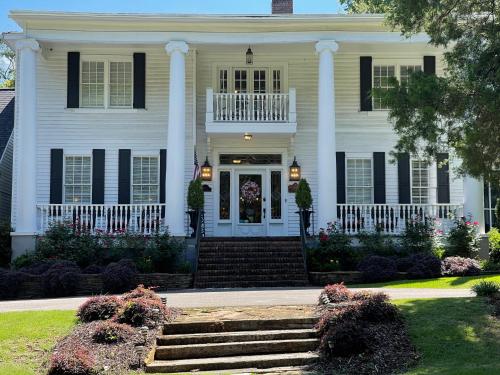 a white house with black shutters and a porch at Bama Bed and Breakfast - Magnolia Family Suite in Tuscaloosa
