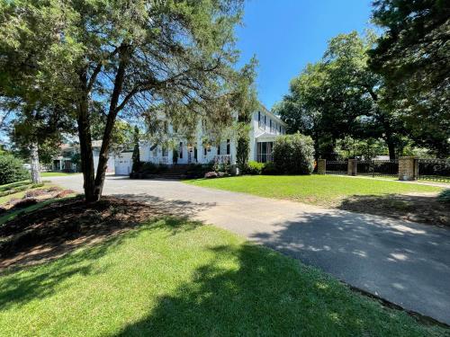 a house with a tree in front of a driveway at Bama Bed and Breakfast - Chimes Suite in Tuscaloosa