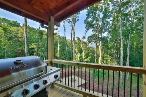 a grill on the deck of a cabin in the woods at Mountain Hideaway with Hot Tub & Fire Pit in Mineral Bluff