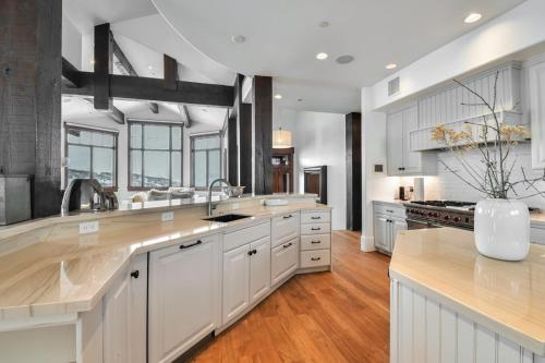 a large kitchen with white cabinets and wooden floors at Deer Hollow Chalet in Park City