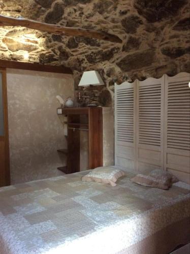 a bedroom with a bed and a stone wall at Bergerie tout confort L'immortelle in Saint-Florent