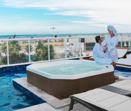 a man and a woman sitting in a hot tub on a balcony at Vidam Hotel Aracaju - Transamerica Collection in Aracaju