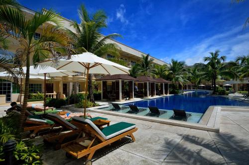 un complexe avec une piscine bordée de chaises longues et un complexe dans l'établissement Henann Garden Resort, à Boracay